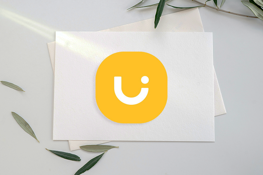 Cartão branco com ícone de carinha sorridente amarelo em fundo claro com folhas verdes dispersas ao redor.